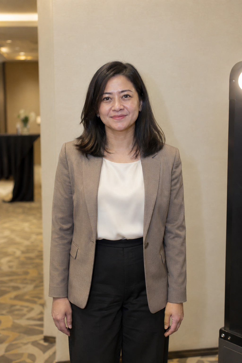 Sample female Business Summit guest in a taupe blazer at a hotel photo booth